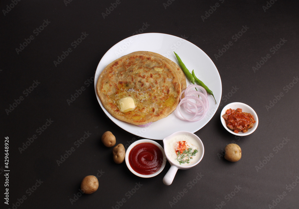 Traditional Indian food Aloo paratha or potato stuffed flat bread. served with pickle  tomato ketchup and curd, butter, onion, chili.