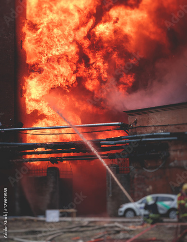 Firefighters put out large massive fire blaze, group of fire men in uniform during fire fighting operation in the city streets, firefighters with the fire engine truck fighting vehicle
