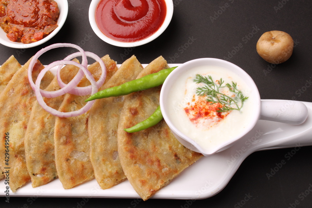Traditional Indian food Aloo paratha or potato stuffed flat bread. served with pickle  tomato ketchup and curd, butter, onion chili.