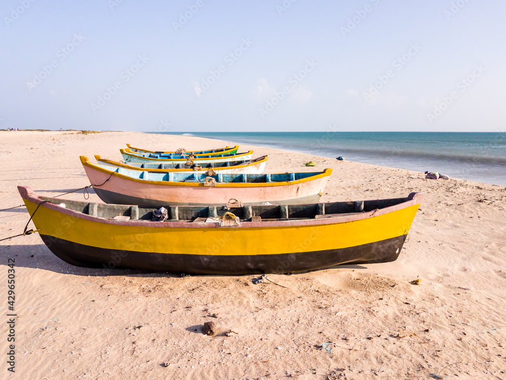Colorful wooden fishing boats idling on a quiet white sand beach in the island of Dhanushkodi near the town of Rameshwaram.