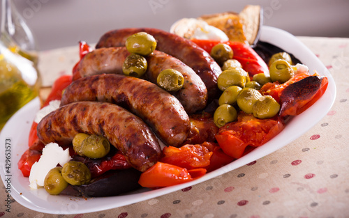 Grilled sausages and vegetables with cottage cheese and olive oil on table