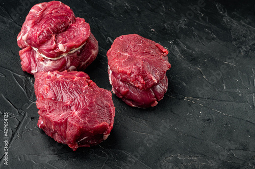 Fillet mignon steak raw, on black stone background, with copy space for text