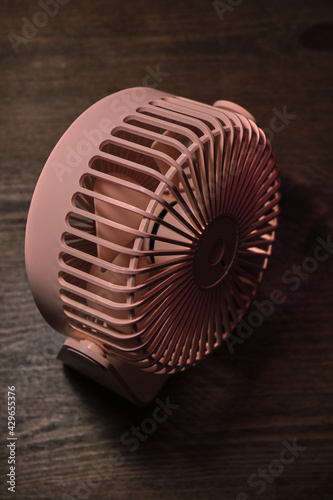pink fan on wooden table folded after fixing