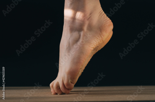 Side view close up of woman dancer bare feet on tip toes on a cork mat and a black background photo