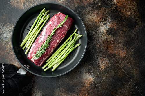 Fresh and raw fillet meat. Whole piece of beef tenderloin steaks, on frying cast iron pan, on old dark rustic background, top view flat lay, with copy space for text