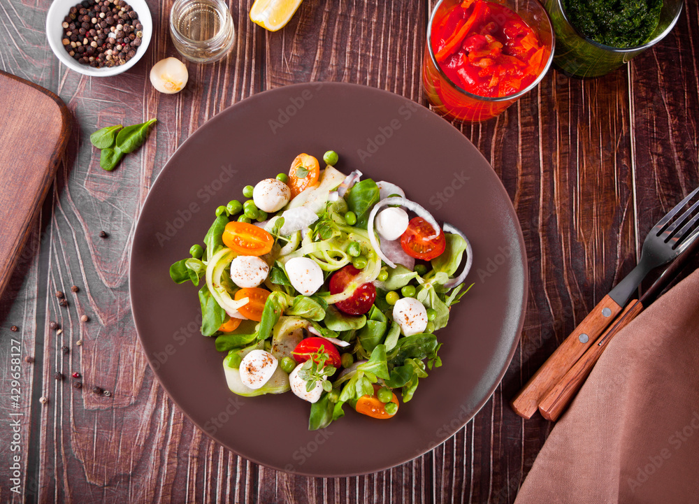 salad of fresh cherry tomatoes, mozzarella, basil, radish and other greens on the dinner table