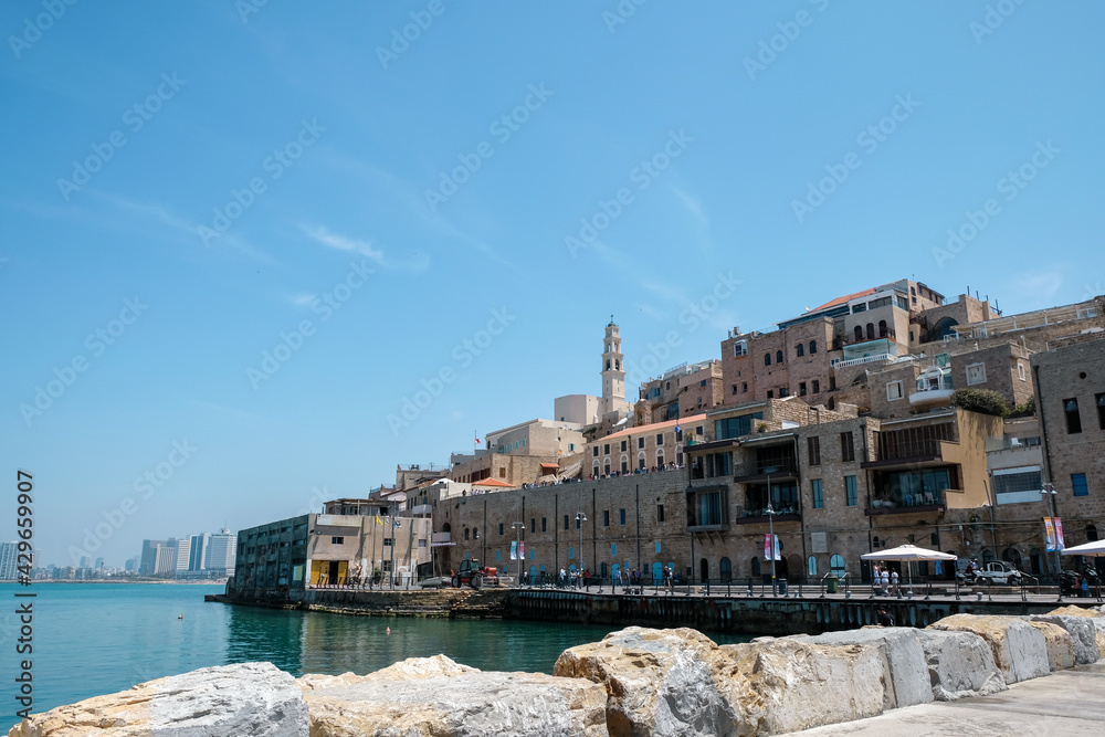 Old town and port of Jaffa and modern skyline of Tel Aviv city in blur background.
