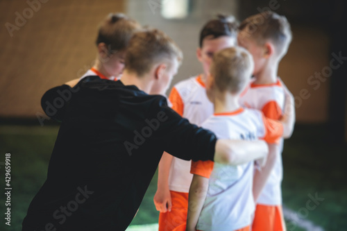 Junior young football team with a coach, group of kids children soccer team having training with trainer instructor, soccer or football coach © tsuguliev