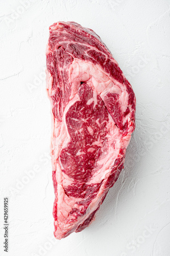 Raw rib eye beef steak marbled meat whole cut, on white stone background, top view flat lay