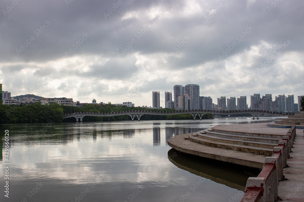 Naklejka premium Skyline with pedestrian bridge over the Linchun River at Sanya, Hainan island, China.