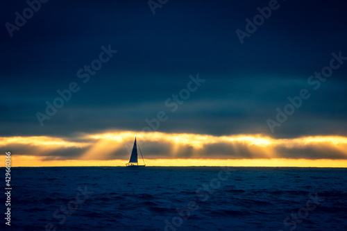 The silhouette of a sailboat is set against a colorful sunset and storm clouds on the Pacific Ocean off the coast of California. © Ashley