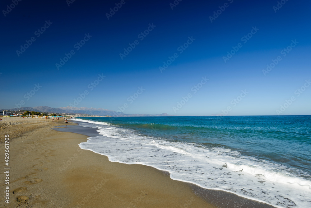 Turquoise sea white foam yellow sand deep blue sky footprints in sand