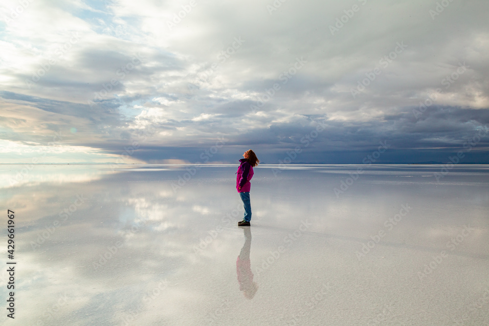 a woman walking on the reflection of the sunrise - obrazy, fototapety, plakaty 