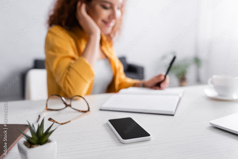 selective focus of smartphone with blank screen near freelancer on blurred background selective focus of smartphone with blank screen near freelancer on blurred background