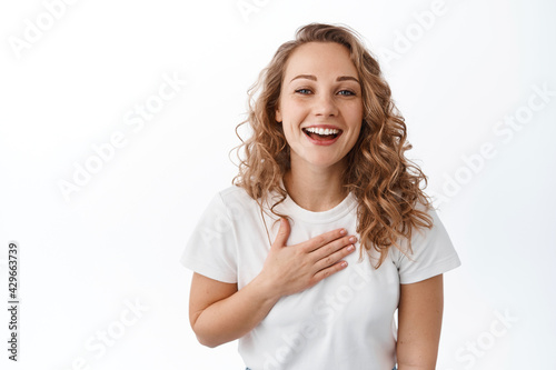 Thank you. Grateful woman smiling and looking pleased and flattered, receive praises, hold hands on heart and thanking, express gratitude, white background