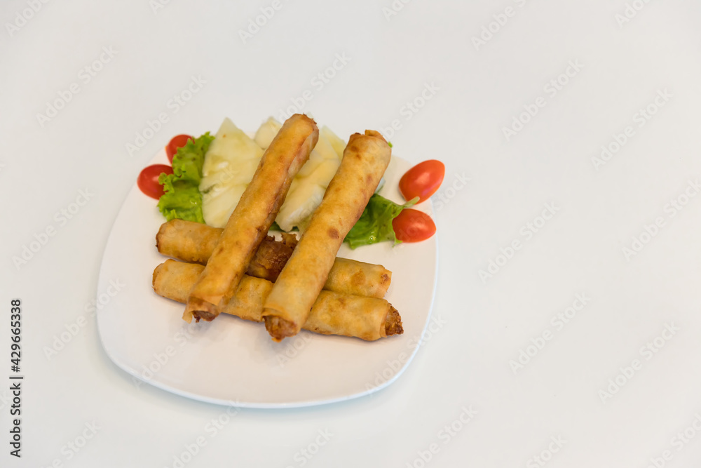 Fried spring rolls with red and white sauces. Deep fried spring roll with sauce on white plate. Crispy spring rolls on dish with vegetable. Fried Chinese Traditional Spring rolls food. Fried spring rolls with red and white sauces. Deep fried spring roll with sauce on white plate. Crispy spring rolls on dish with vegetable. Fried Chinese Traditional Spring rolls food.