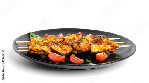 Chicken skewers with vegetables on black plate isolated on a white background. Souvlaki isolated.