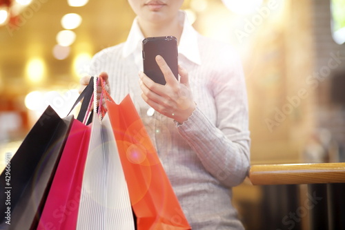 Woman carrying shopping bags and using smartphone