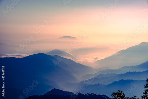 View of Himalayas mountain range with visible silhouettes through the colorful fog at Binsar  a hill station in Almora district  Uttarakhand  India.