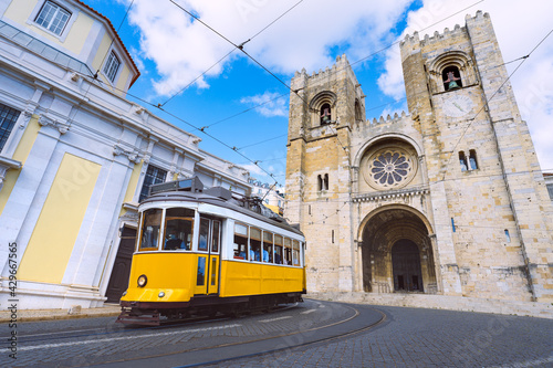 Lisbon city and famous yellow tram 28 in front of Santa Maria cathedral on a sunny summer day. Trams in Lisbon, Portugal. Tourist attraction