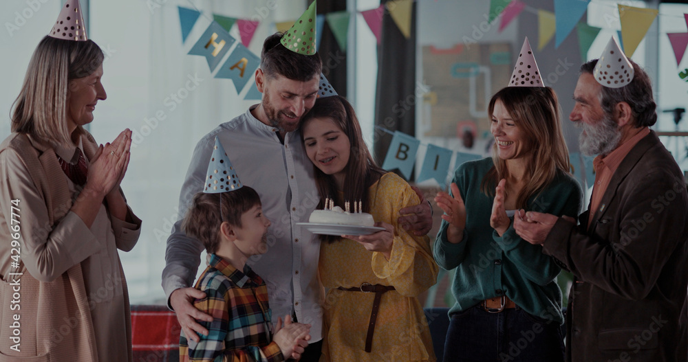 Happy multi-generation family of four members celebrating birthday party with candle cake blowing and enjoying reunion holiday. - obrazy, fototapety, plakaty 