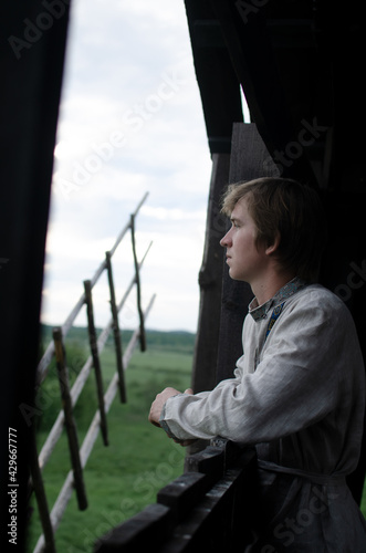 Downshifting concept. A young guy in national clothes lives in an eco-village and earns money from it