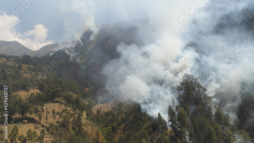 fire in mountain forest. aerial view forest fire and smoke on slopes hills. wild fire in mountains in tropical forest  Java Indonesia. natural disaster fire in Southeast Asia