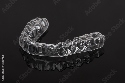 Invisible orthodontics cosmetic brackets on black background. Tooth aligners, for beautiful smile.
