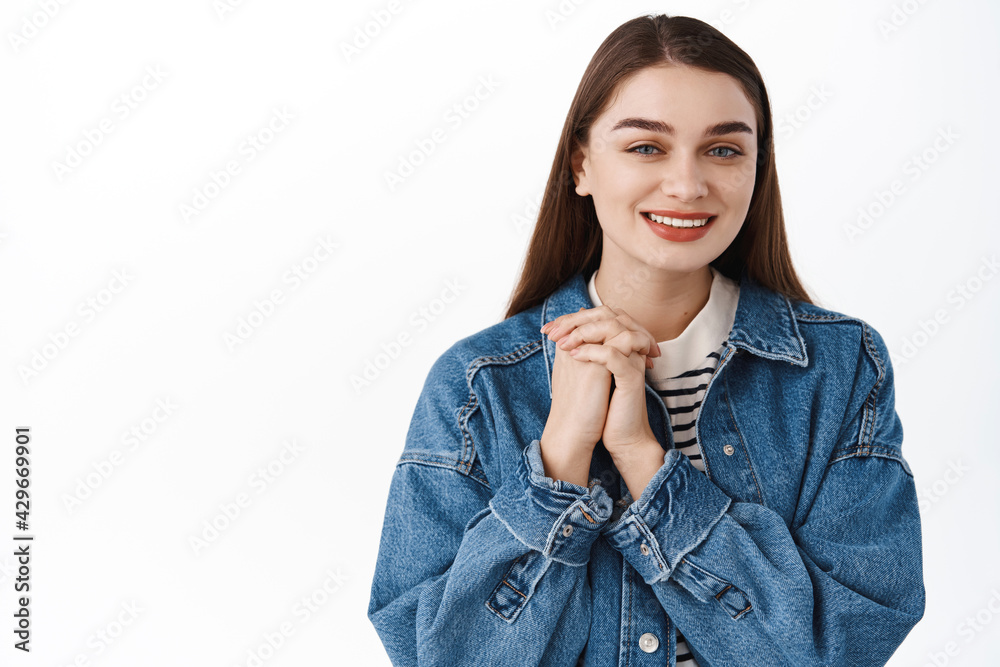Thank you. Smiling cute girl holding hands together and looking pleased and thankful, express gratitude, feeling delighted, standing near copy space for logo banner, standing over white background Thank you. Smiling cute girl holding hands together and looking pleased and thankful, express gratitude, feeling delighted, standing near copy space for logo banner, standing over white background