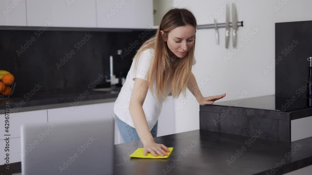 Blonde girl sweap kitchen surfaces on kitchen counter with a cloth Blonde girl sweap kitchen surfaces on kitchen counter with a cloth