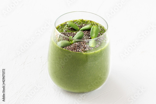 Raw green smoothie with microgreens alfalfa sprouts and chia seeds in a glass on white background.