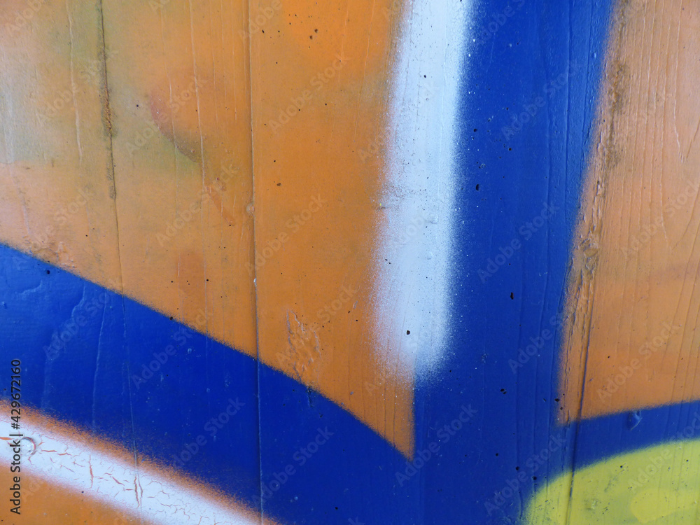 Naklejka premium Orange, blue, white and yellow sprayed on a concrete wall