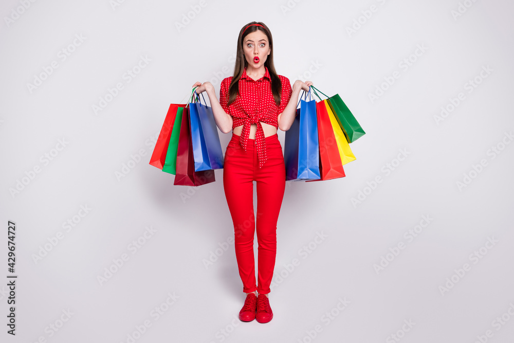 Photo of pretty surprised girl hold many packets wear red dotted blouse pants footwear isolated grey color background