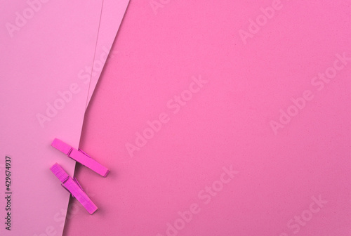 Pink pastel blank paper with wooden clips, pegs. Abstract minimal paper texture background. Free space for your text, image or design. Top view, horizontal image style.