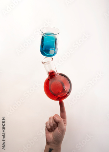 Flat bottom flask and a Berzelius beaker glass balanced on top of fingertip photo