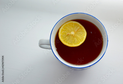 there is a large mug with hot tea on a light background, a lemon slice is floating in the mug
