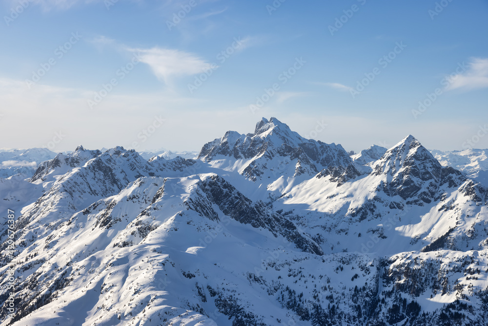 Obraz premium Aerial View from Airplane of Blue Snow Covered Canadian Mountain Landscape in Winter. Bright Sunny Sky. Tantalus Range near Squamish, North of Vancouver, British Columbia, Canada. Authentic Image.