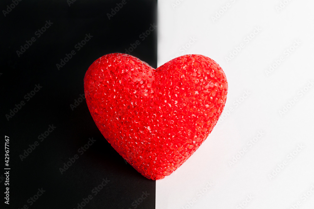 Fototapeta premium Red heart on black and white background. The heart is in the middle.