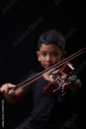 Young boy play the violin on black background