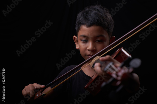 Young boy play the violin on black background
