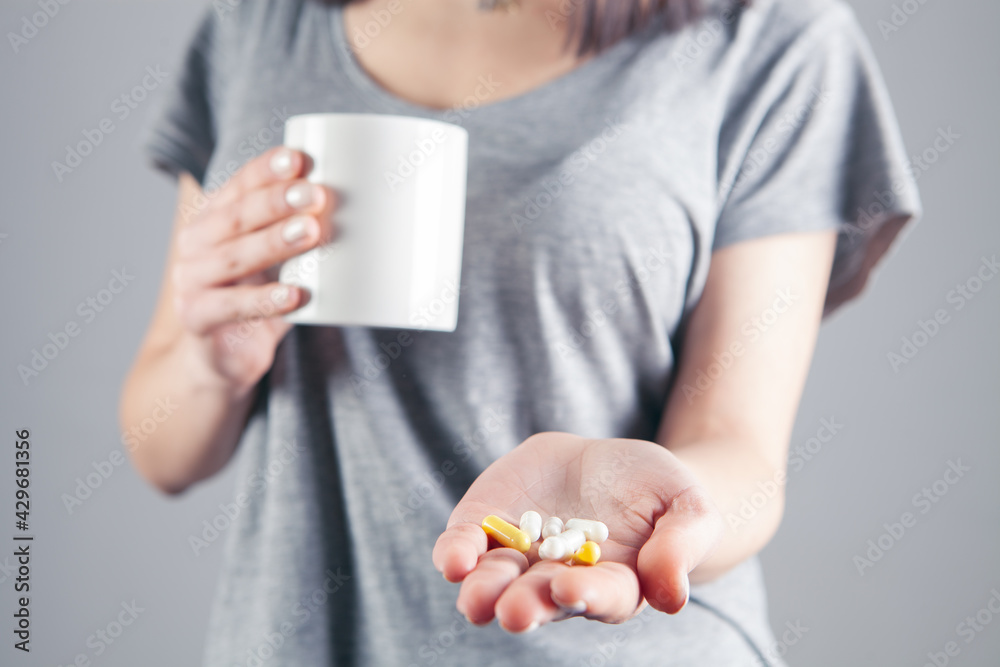 Woman holding pill and glass of water in hands taking emergency medicine Woman holding pill and glass of water in hands taking emergency medicine