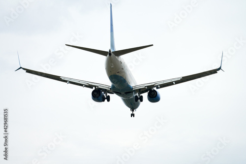 A passenger plane with the landing gear released is landing. Copy space.