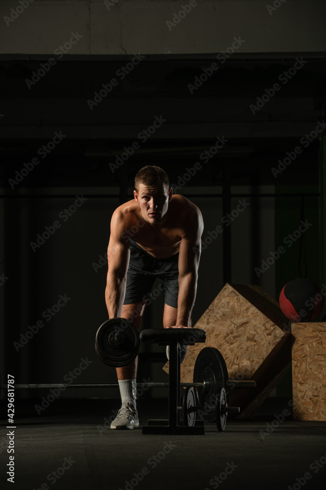 Sportsman doing exercises with weights over fitness bench and looking straight at the camera. Sportsman doing exercises with weights over fitness bench and looking straight at the camera.