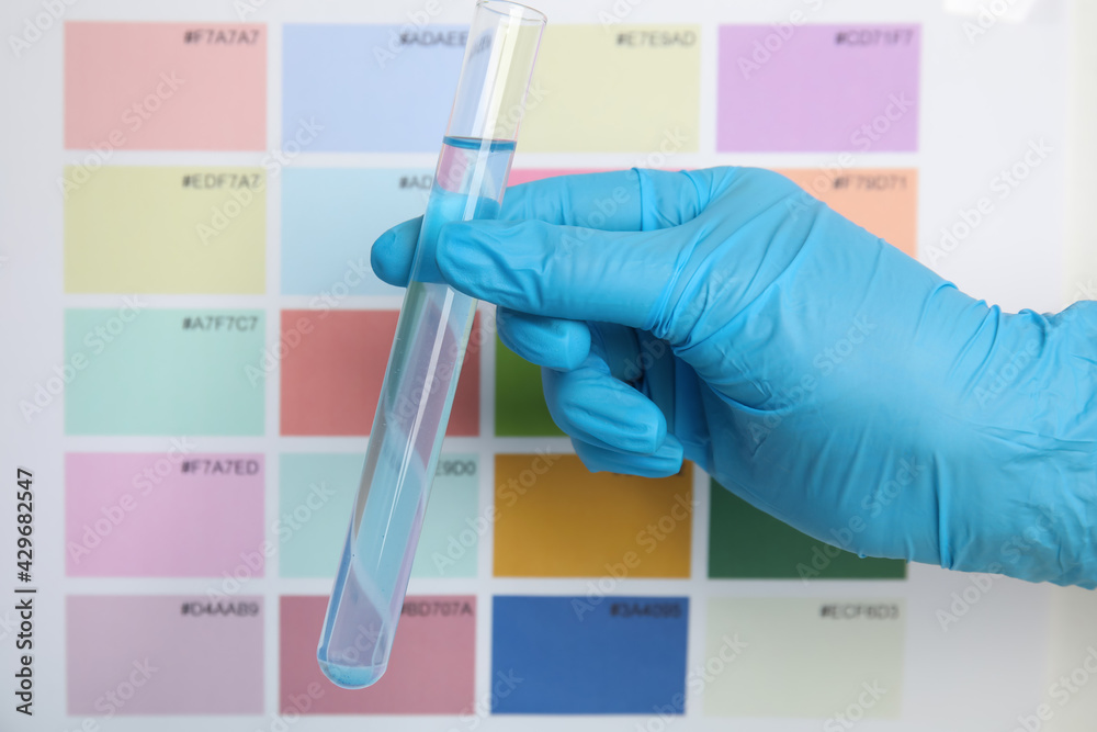 Fototapeta premium Doctor holding test tube with liquid near sample chart, closeup