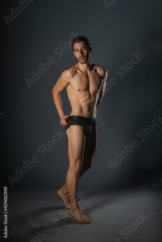 Naked young sexy man posing in black underwear in a studio © qunica.com