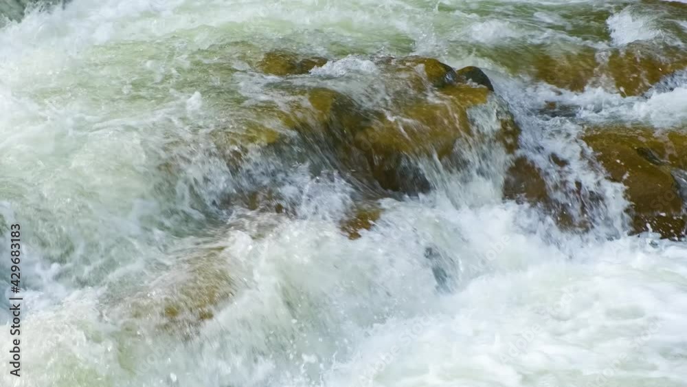 Mountain river with clear turquoise water falling down in cascades between wet boulders with thick white foam. Mountain river with clear turquoise water falling down in cascades between wet boulders with thick white foam.