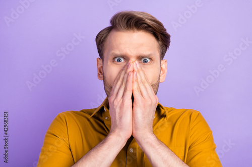 Photo of shocked worried man hands palms cover face nose look camera isolated on violet color background