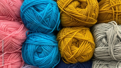 Blue, yellow and pink range of wool yarn. Multicolored skeins of wool close-up