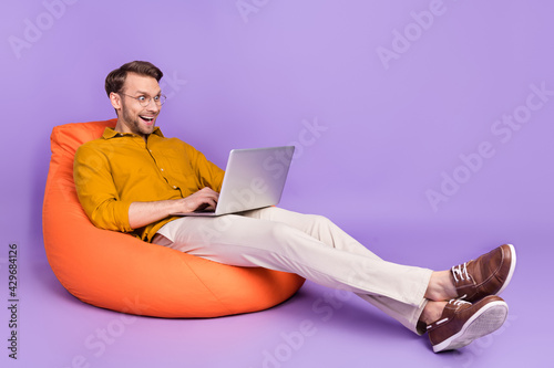Full body profile side photo of young man happy positive smile work laptop programmer isolated over purple color background