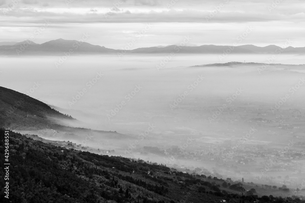 Mist and fog between valley and layers of mountains and hills at dusk, in Umbria, Italy